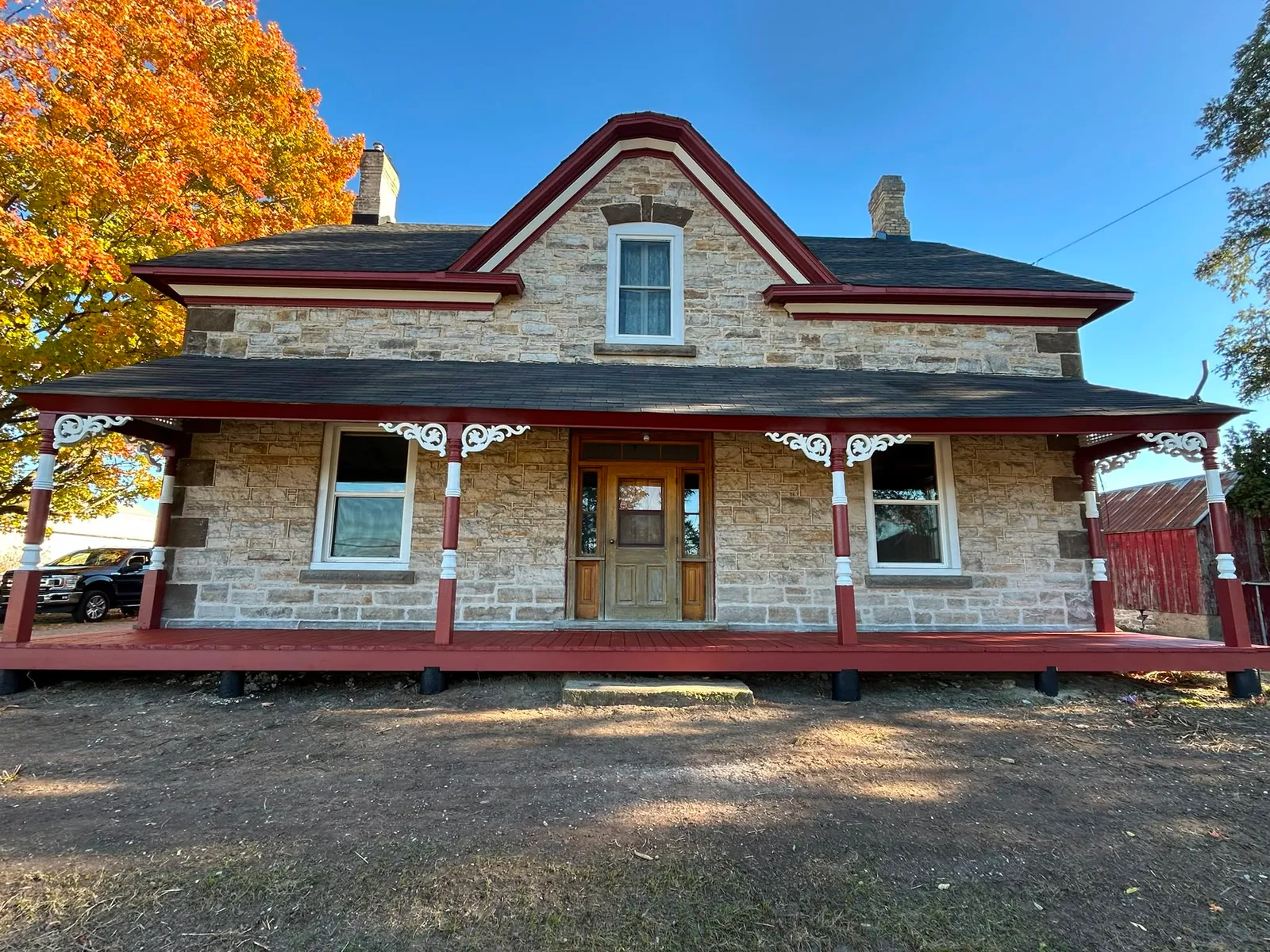 Heritage stone farmhouse with a freshly painted red porch and trim by McIntosh Painting & Maintenance in Lanark County