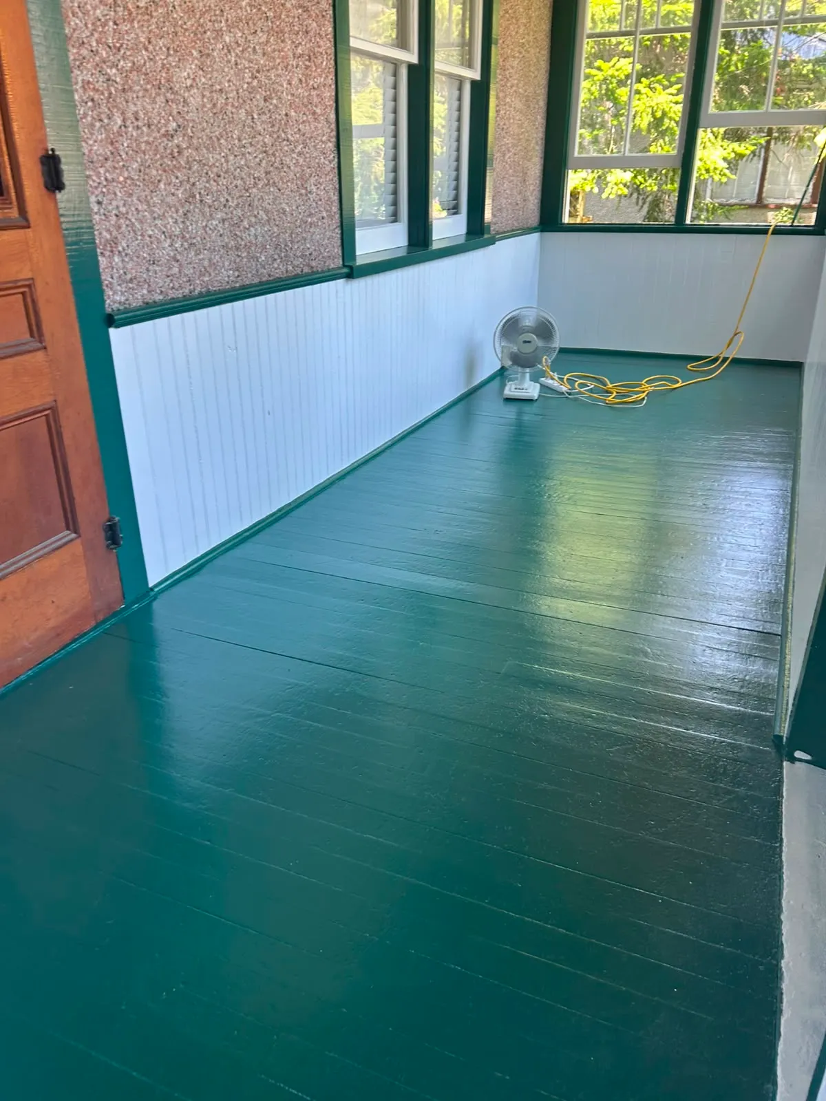 A freshly painted glossy green porch floor finished by McIntosh Painting & Maintenance