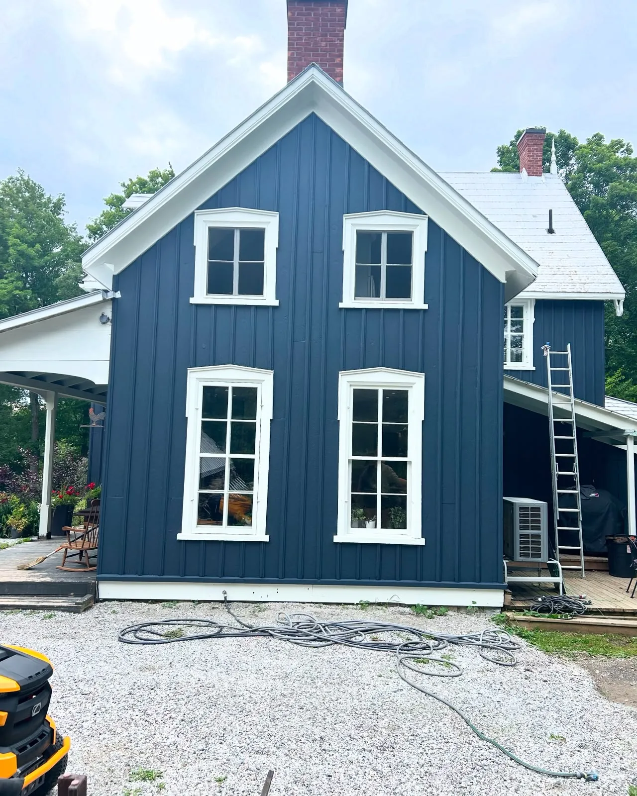 Navy board-and-batten farmhouse with crisp white trim, freshly painted, in Lanark County